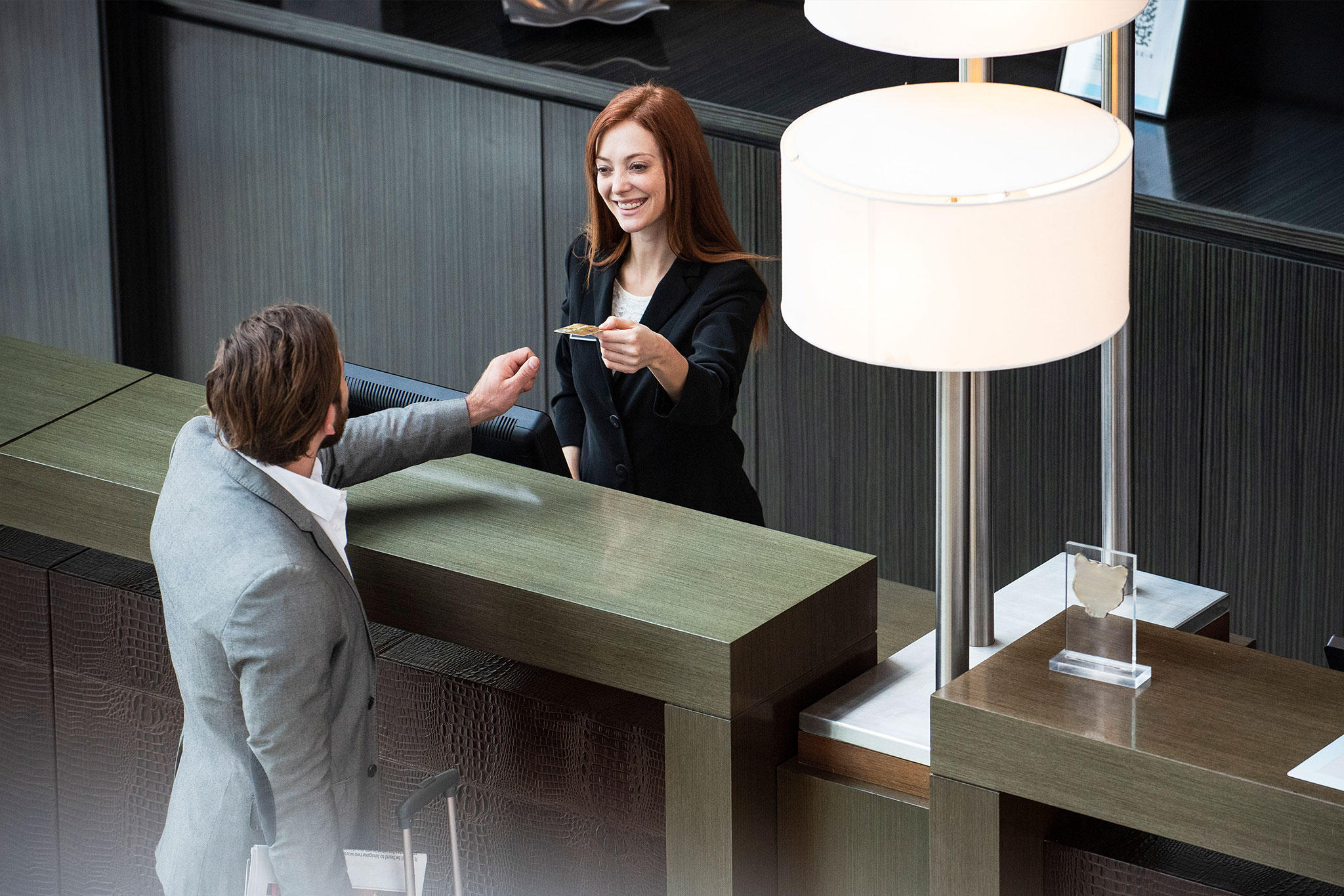 man checking into a hotel. Hotel clerk giving man room key